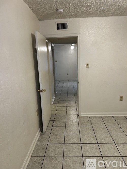 A hallway with a tiled floor and a door at the end.