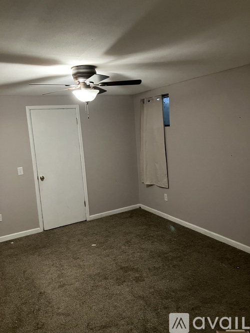 A room with a ceiling fan and a door.