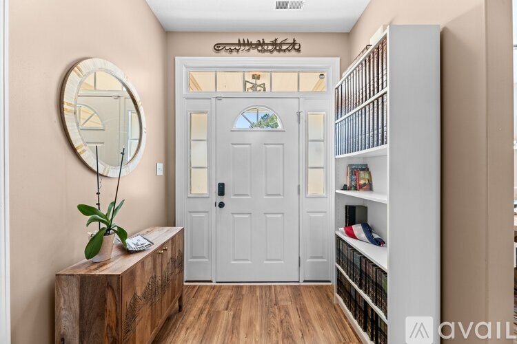 A room with a white door and a round mirror on the wall.