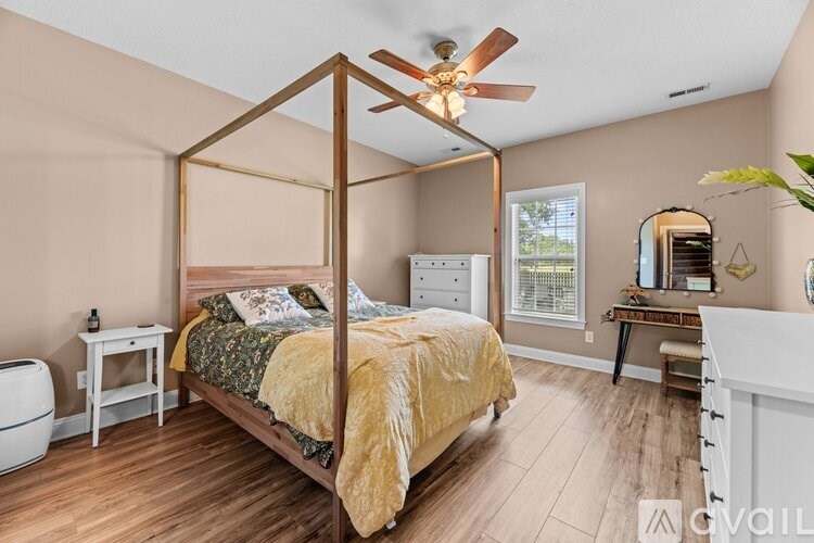 A bedroom with a four-poster bed and a ceiling fan.