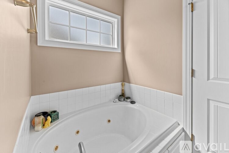 A white bathtub with a window above it in a bathroom.