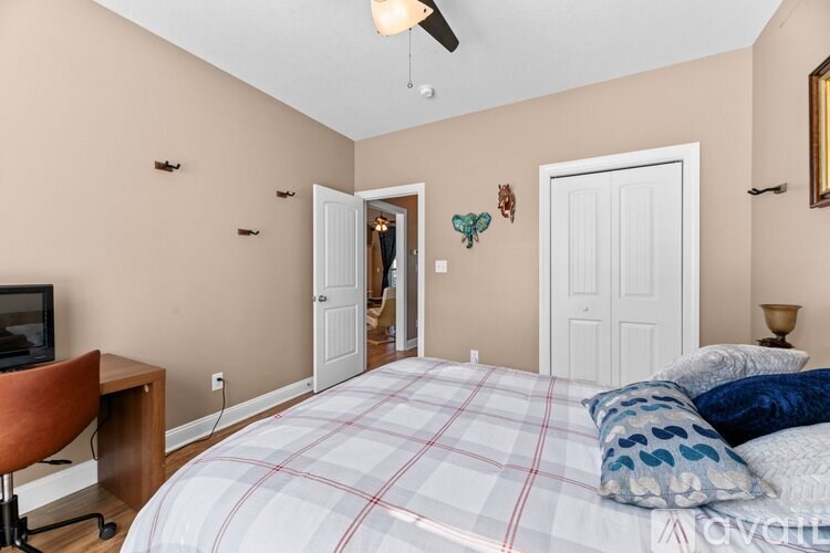 A bedroom with a bed, chair, and a television.