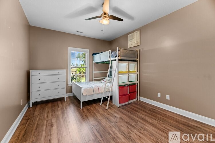 A bedroom with a bed, dresser, and a window with a view of trees.