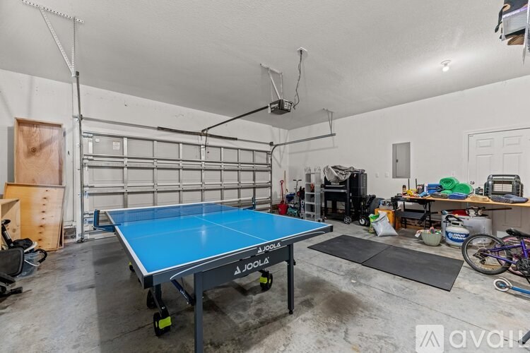 A blue Joola table tennis table is in the middle of a garage.