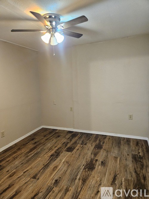A room with a ceiling fan and wooden flooring.