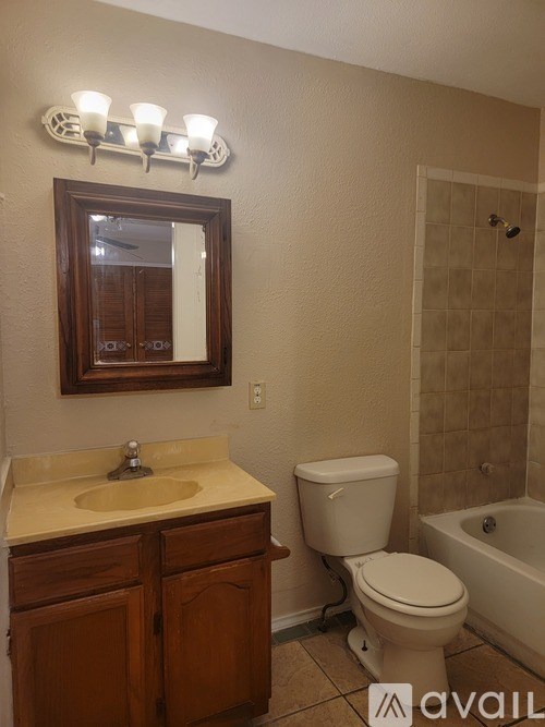 A bathroom with a toilet, sink, mirror, and tub.