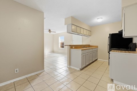 A kitchen with white cabinets and a black fridge.