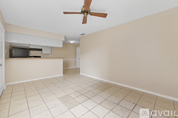A room with a ceiling fan and a flat screen TV mounted on the wall.