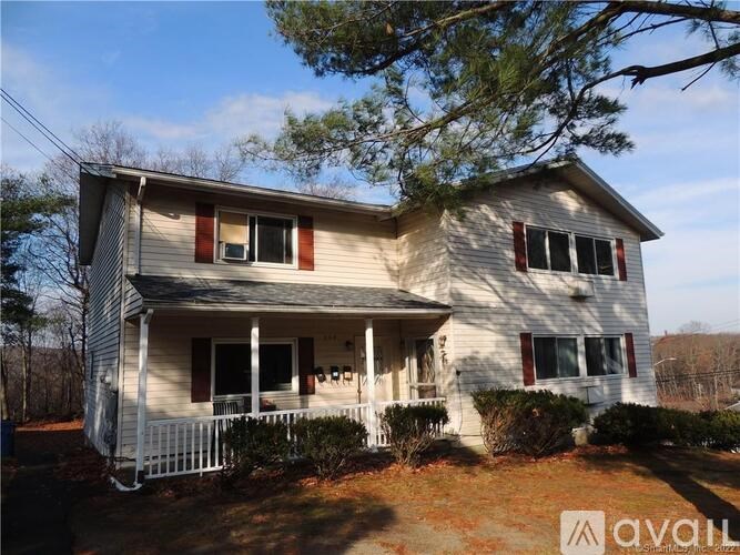 A two-story house with a white fence and red shutters is for sale.