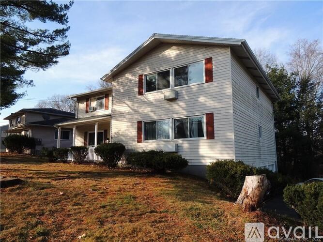 A two-story house with a beige exterior and red shutters.