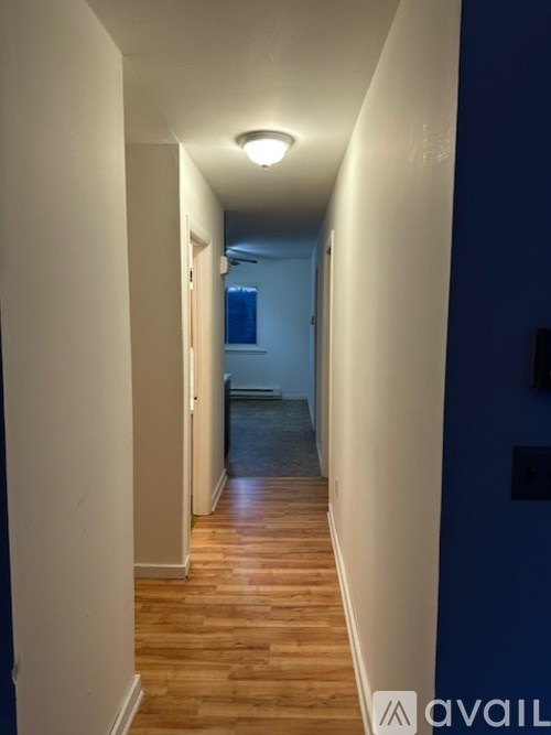 A long hallway with wooden floors and white walls.