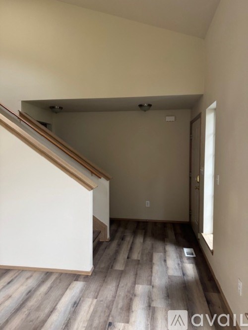 A room with wooden flooring and a staircase leading to another level.
