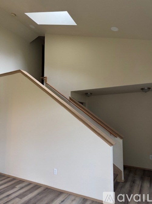 A staircase with a wooden handrail and a skylight above it.