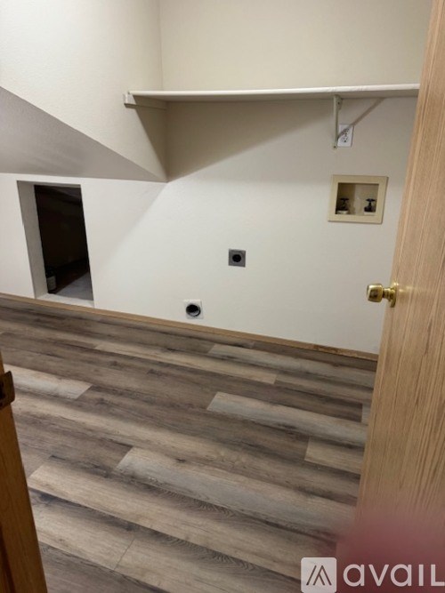 A room with a wooden floor and a white wall with a small picture frame on it.