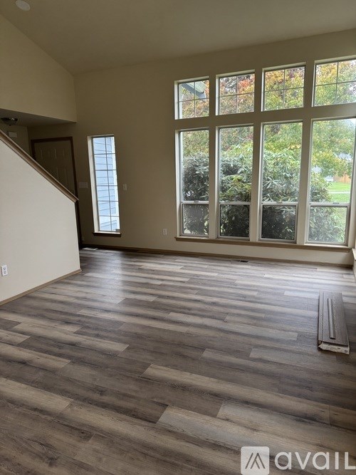A room with wooden flooring and a large window overlooking a garden.