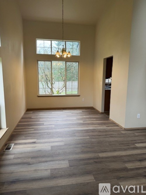 A spacious room with wooden flooring and a large window.