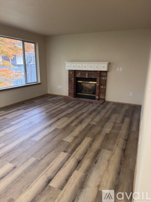 A room with a fireplace and wooden flooring.