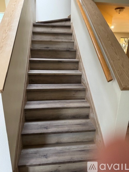 A wooden staircase with a white wall on the side.