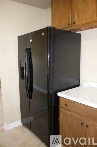 A black refrigerator in a kitchen with wooden cabinets.