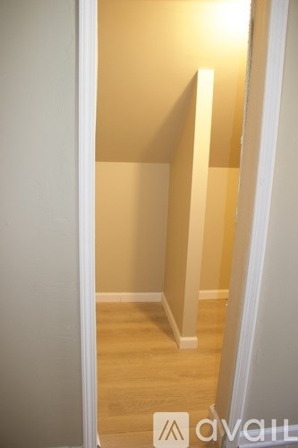 A hallway with a wooden floor and white walls.