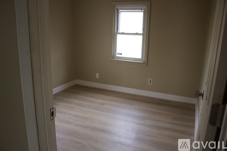 A room with a window and wooden flooring.
