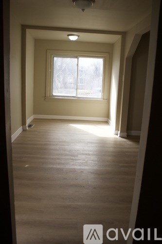 A room with a window and wooden flooring.