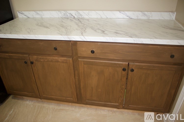 A kitchen counter with wooden cabinets and a marble top.