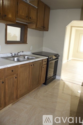 A kitchen with wooden cabinets and a black dishwasher.