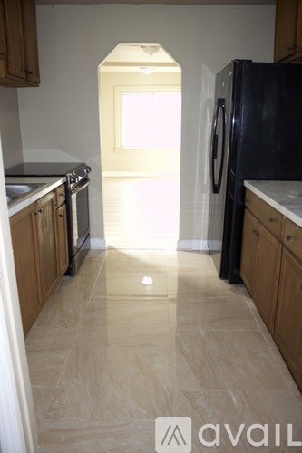 A kitchen with a black fridge and wooden cabinets.