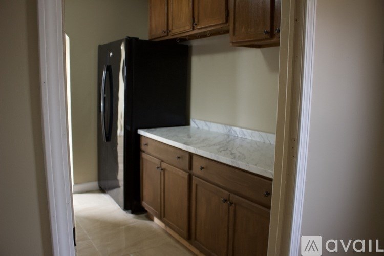 A black fridge in a kitchen with wooden cabinets.