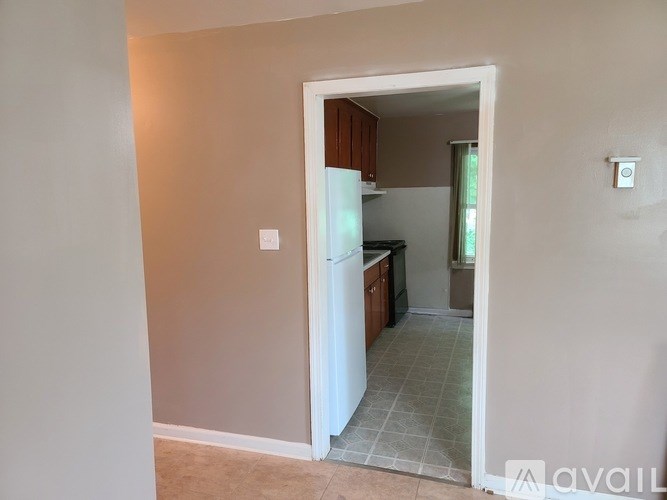A kitchen with a white refrigerator and wooden cabinets is visible through an open door.
