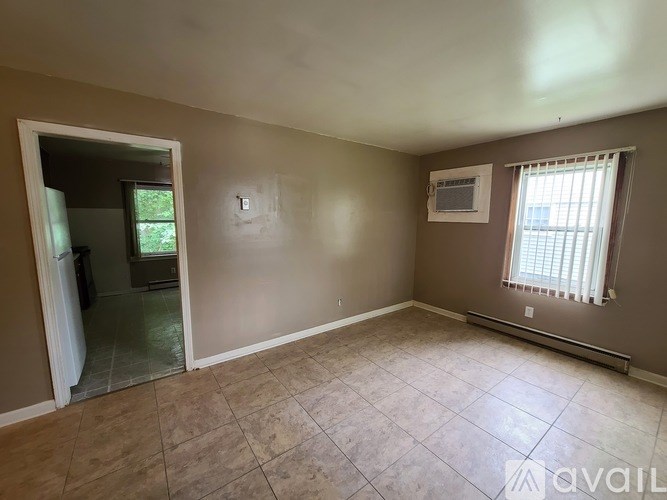 A room with beige walls and a tiled floor is available for rent.