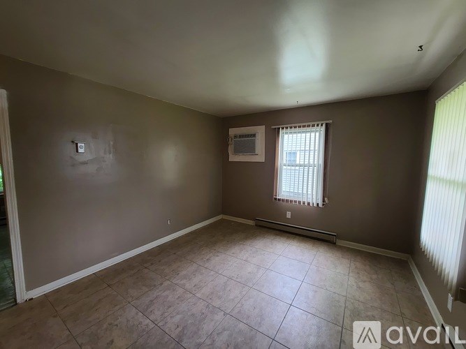 Empty room with tile flooring and a window with blinds.
