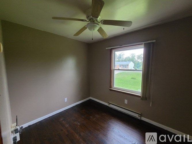 A room with a ceiling fan and a window overlooking a green lawn.