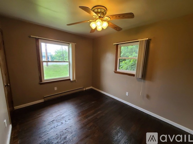 A room with a ceiling fan and two windows.