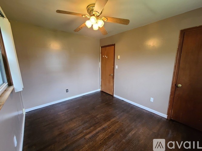 A room with a ceiling fan and wooden floors.