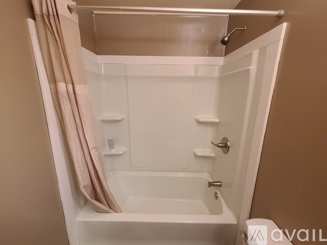 A white bathtub with a shower curtain and a towel rack.