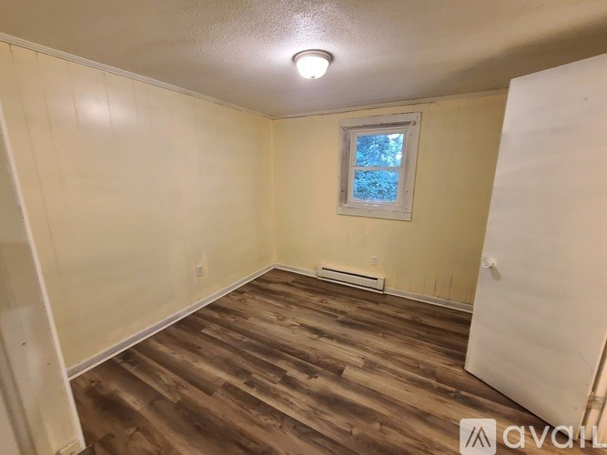 A room with wooden flooring and a window with a white frame.