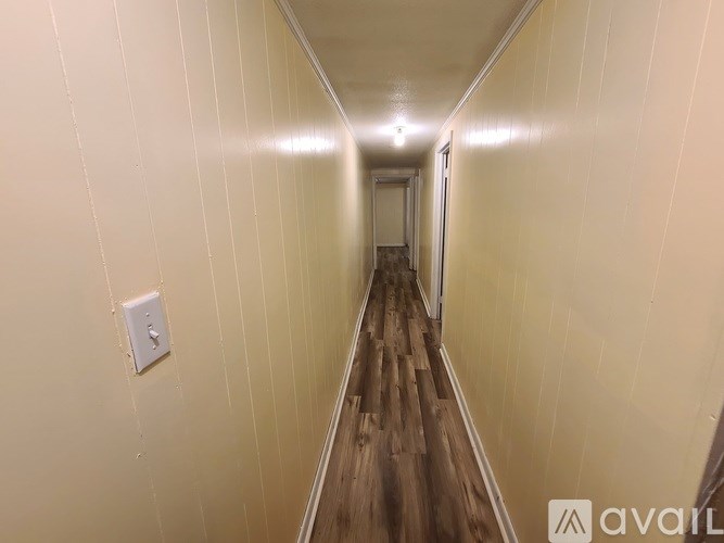 A long hallway with wooden floors and white walls.
