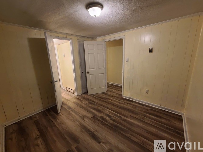 A room with wooden floors and three doors.