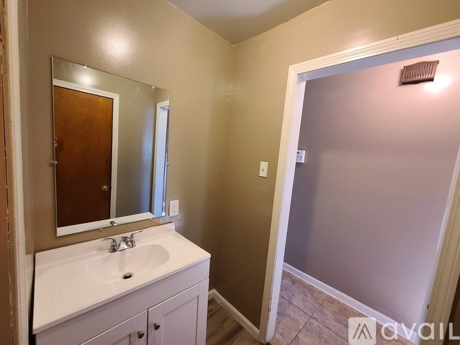 A bathroom with a sink, mirror, and a door.