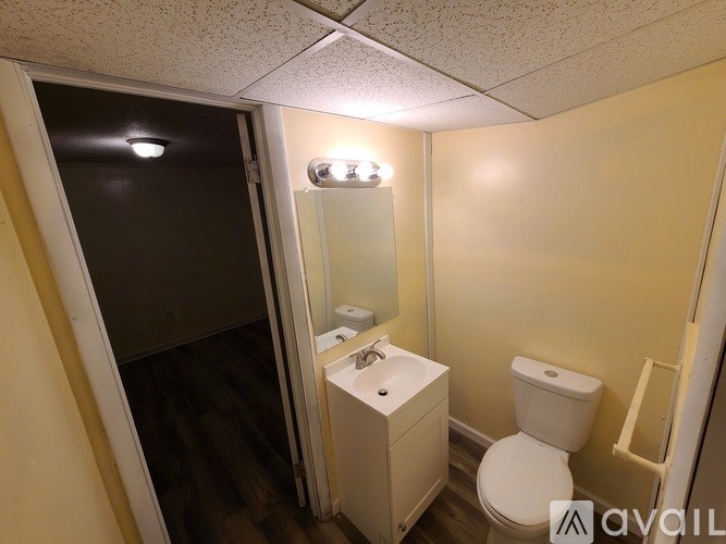 A small bathroom with a toilet, sink, and mirror.