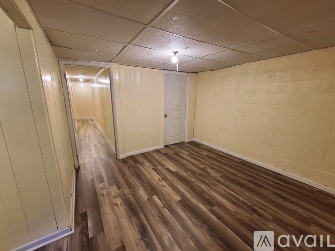 A room with wooden flooring and a doorway leading to another room.