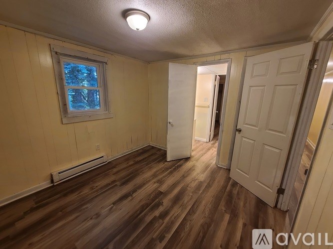 A room with wooden floors and a window with a view of trees outside.