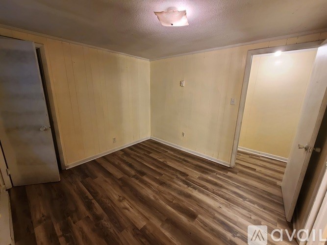 A room with wooden flooring and white walls.