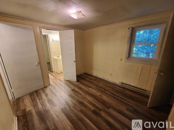 A room with wooden floors and a window with a view of trees outside.