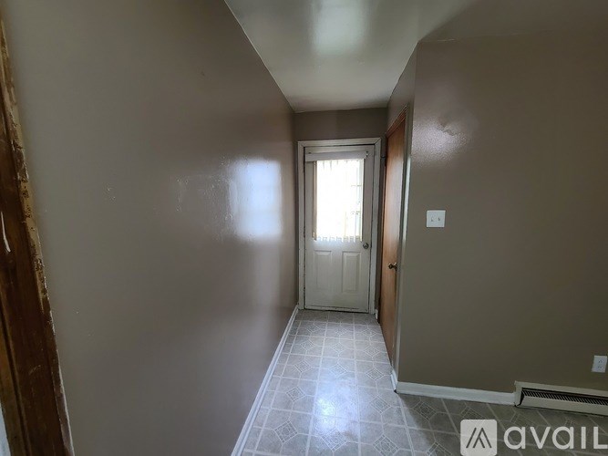 A hallway with a door at the end and a tiled floor.
