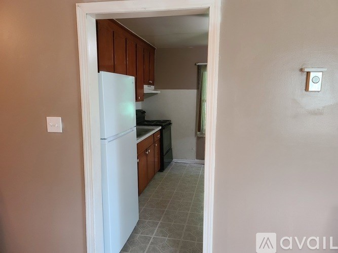 A kitchen with a white fridge and brown cabinets.