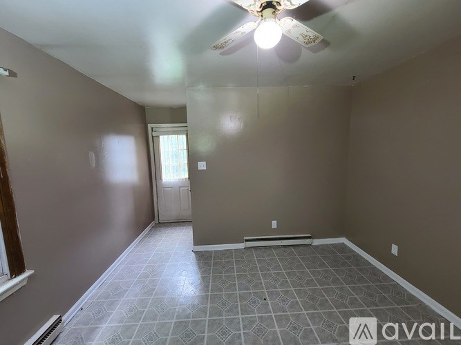 A room with a ceiling fan and tile flooring.