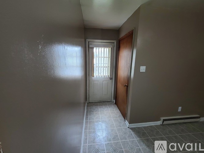A hallway with a door and a tiled floor.
